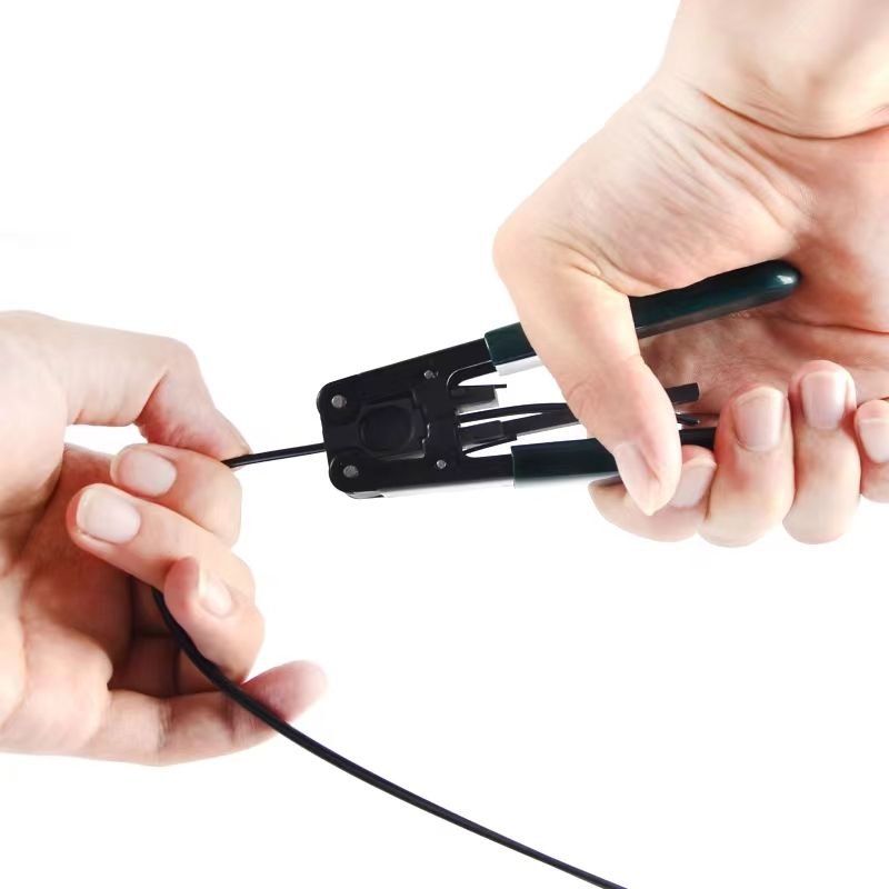 Two hands using a Flat Drop Wire Stripper to prepare a fiber optic cable