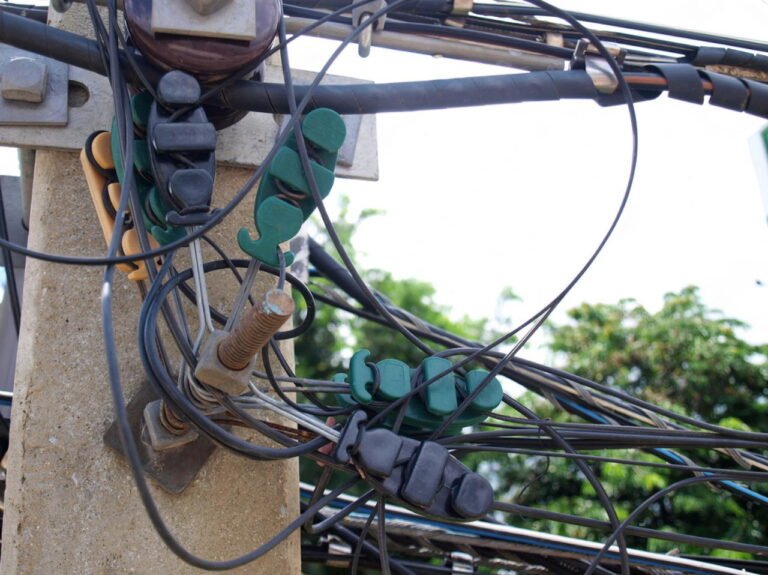 Telecom Hardware: cables secured with green and black clamps on a utility pole