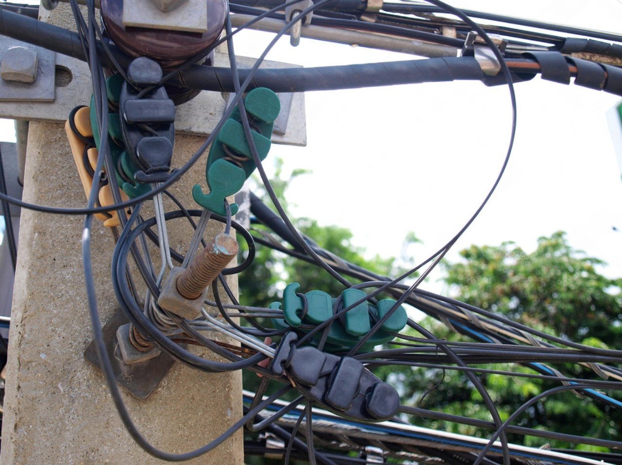 Telecom Hardware: cables secured with green and black clamps on a utility pole