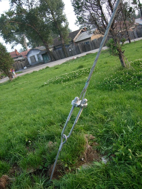 A stay wire connected to the ground, showing stay wire hardware components