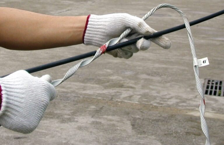 Hands wearing white gloves installing a preformed tension clamp, ADSS/OPGW fittings, onto a black cable