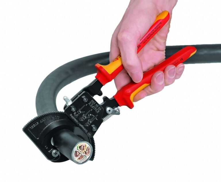 A hand uses a cable cutter to strip the outer layer of a thick black cable, revealing the inner wires
