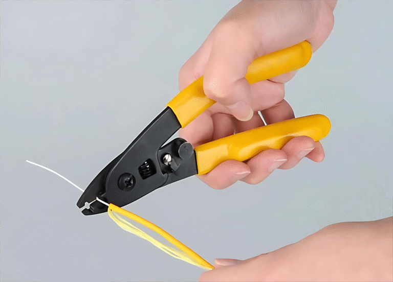 A person using a yellow-handled Optical Fiber Stripper to remove the outer jacket from a yellow fiber optic cable.
