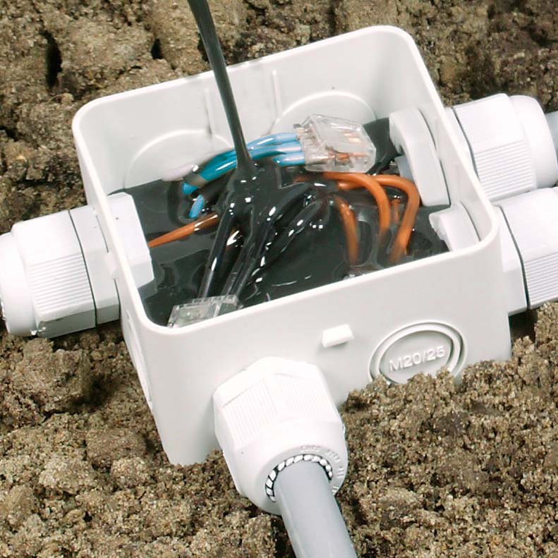 A waterproof electrical junction box is being filled with a black sealant to protect internal wiring connections from moisture and environmental factors