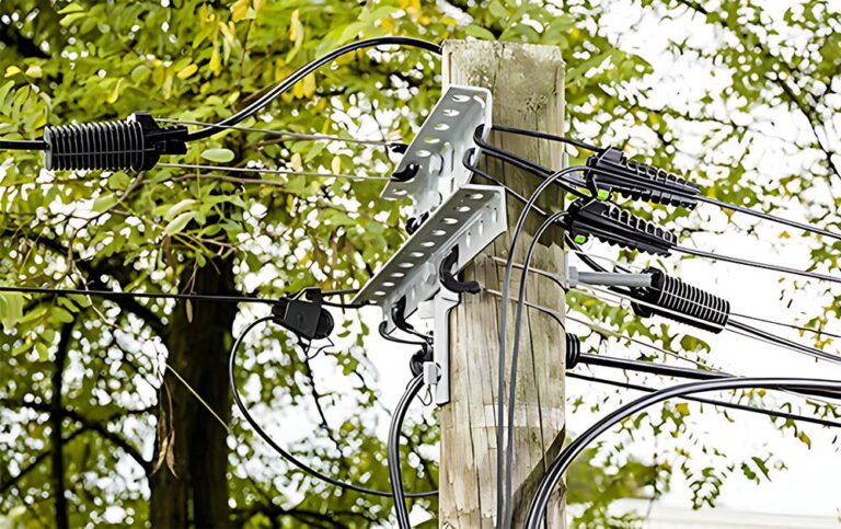 a utility pole with multiple aerial fiber optic cables anchored by a Fiber Optic Tension Clamp