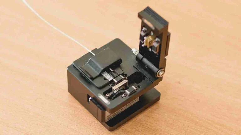 A professional-grade, black Optical Fiber Cleaver with a fiber optic cable secured in its V-groove, ready for the high-precision scribing and breaking process