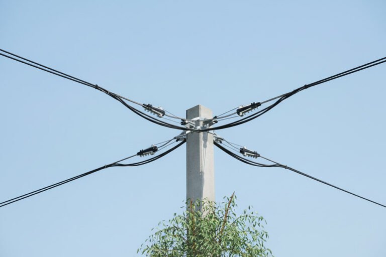 An NXJL Anchoring Clamp installed on a utility pole, securing an overhead power line against a clear blue sky.