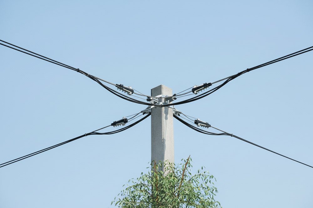 An NXJL Anchoring Clamp installed on a utility pole, securing an overhead power line against a clear blue sky.